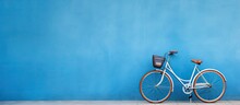 A High-quality Photo Of A Bicycle Is Positioned Against A Blue Wall, With Empty Space Available