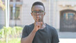 © stockbakers - Outdoor Portrait of Young African Man with Finger on Lips