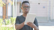 © stockbakers - Young African Man using Tablet Outdoor