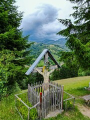 Sticker - Wooden cross stands atop a hill, with lush rolling green hills extending out in the background