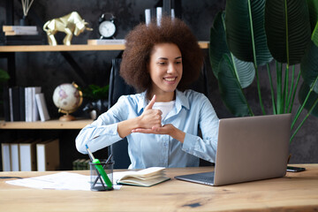 Young deaf african-american businesswoman have digital virtual online conference with employees on computer, talking on video call, using sign language