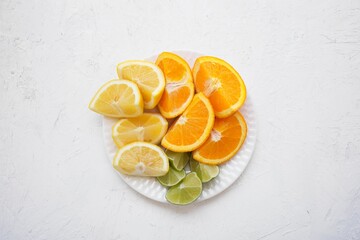 Wall Mural - Top view of several citrus fruits arranged on a plain white plate.