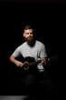 © Volodymyr - Bearded brutal guitarist plays an acoustic guitar in a black room.