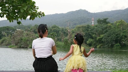 Wall Mural - Mother and daughter on the park bench playing soap bubble.