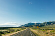 Beautiful road landscape with road signs, mountains, highway and blue sky with fluffy clouds on a sunny summer day. American landscape with a wide highway