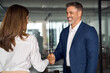 © Stock 4 You - Mature Latin business team of woman and European business man shaking hands as colleagues, partners or employees, signing a contract. Group of people satisfied with results of team work together.