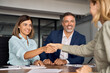 © Stock 4 You - Mature Latin business team of woman and European business man shaking hands with colleagues, partners or employees, signing a contract. Group of people satisfied with results of team work together.