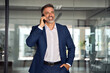 © Stock 4 You - Middle aged Latin or Indian businessman having call on smartphone with business partners or clients. Smiling mature Hispanic man in relaxing pose talking by mobile cellphone at work in modern office.