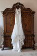 A white wedding dress hung on a antique wardrobe
