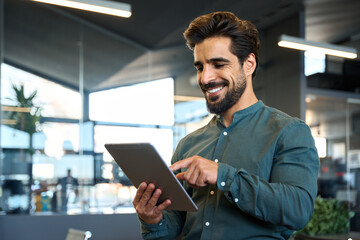 happy young latin business man executive holding pad computer at work. male professional employee us
