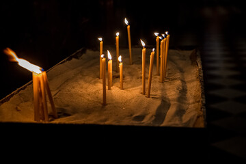 Burning church candles gilded candlestick temple dark