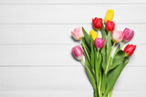 Fototapeta Tulipany - Beautiful colorful tulip flowers on white wooden table, flat lay. Space for text