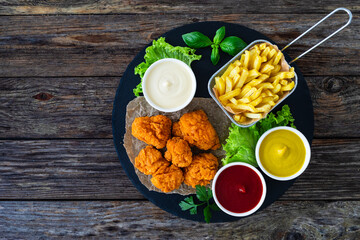 Wall Mural - Seared breaded chicken nuggets with French fries on wooden table
