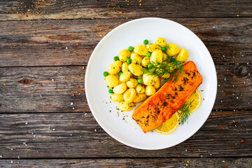 Seared salmon steak with gnocchi and lemon slices served on wooden table
