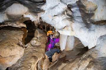 Wall Mural - Young woman spelunking inside a cave. Feminism concept. Concept of women's sport.