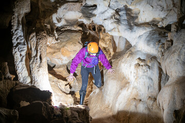 Wall Mural - Young woman spelunking inside a cave. Feminism concept. Concept of women's sport.