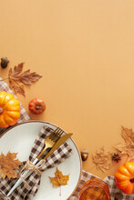 Fall-themed Table Setup Idea. Top View Vertical Shot Of Plate, Cutlery, Checkered Napkin, Tablecloth, Glass, Pumpkins, Anise, Acorns, Maple Leaves On Pastel Brown Background With Space For Ad Or Text