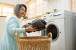 © Kiattisak - Asian Senior woman housekeeper loading clothes to washing machine. Routine activity in house concept.