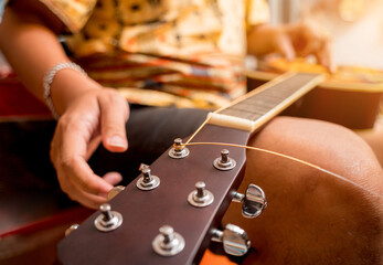 Wall Mural - Young musician changing strings on a classical guitar in a guitar shop