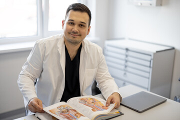 Wall Mural - Portrait of urologist sitting with a book in a medical office. Concept of portraits of real doctors