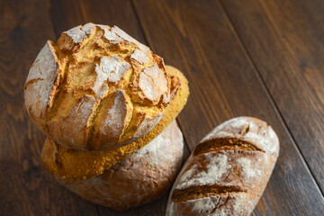 Canvas Print - Stack of different loaves of bread on a wooden table with copy space