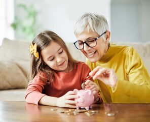 Wall Mural - child money saving grandfmother family coin senior finance bank piggybank happy investment granddaughter girl financial elderly cash