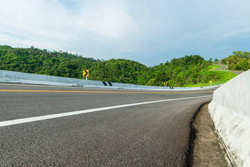 Wall Mural - Long curvy forest asphalt road over the hills. Beautiful curved road in the forest. Side view of road.