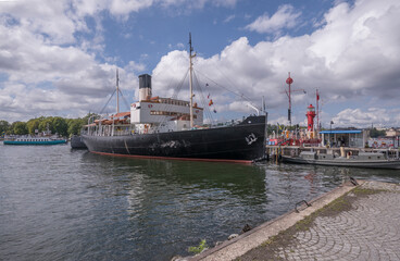 Pier with museums boats, icebreaker St Erik, lighthouse ship and a steam boat sloop, a sunny summer day in Stockholm