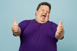 © ViDi Studio - Young smiling happy satisfied cheerful chubby cool overweight man wear purple t-shirt casual clothes show thumb up look camera isolated on plain pastel light blue cyan background. Lifestyle concept.