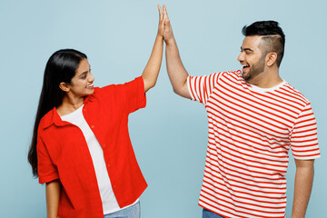Wall Mural - Young couple two friends family Indian man woman in red casual clothes t-shirts together meeting together greeting giving high five clapping hands folded isolated on plain blue cyan color background