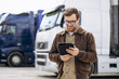 © Petro - Truck driver standing by his lorry and using tablet