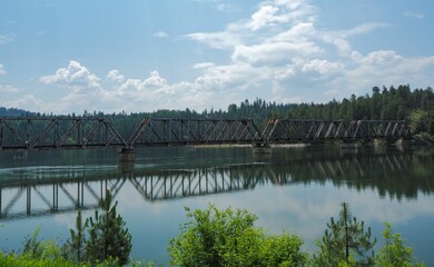 Sticker - Bridge crossing over a tranquil body of water on the background of lush green trees