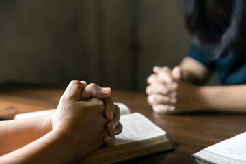 Christian family praying together concept. Child and mother worship God in home. Woman and boy hands praying to god with the bible begging for forgiveness and believe in goodness.