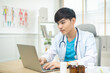 © anon - Young asian man wearing doctor uniform smiling confident at clinic,looking and smiling at camera...