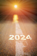 2024 on road surface with white marking line leading into abstract blur sunlight and sun. Start to success concept and sustainable lifestyle idea