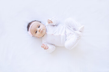 baby girl smiling on the bed on a white isolated background on a cotton bed, falling asleep or wakin