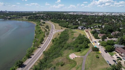 Canvas Print - Aerial footage of road and city with trees has a beautiful river view under cloudy sky