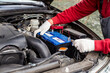 © Natalia - a car mechanic installs a battery in a car. Battery replacement and repair
