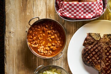 Wall Mural - Wooden dining table with delicious steak and baked beans