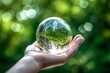 Glass globe in hand on nature background, save the world concept. Transformative power. Gossy globe in hand.