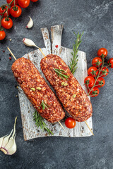 Wall Mural - raw Lula kebab on skewers with spices on a wooden board, vertical image. top view. place for text