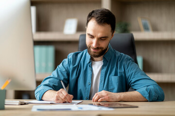 Aufkleber - Smiling Handsome Businessman Taking Notes To Notepad At Workplace In White Office