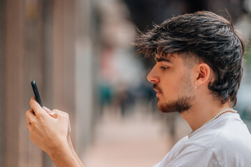 Sticker - portrait of young man in the street looking at the mobile phone