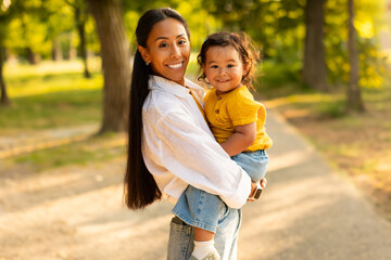 Wall Mural - Loving Asian Mom Embracing and Holding Adorable Baby Daughter Outdoors