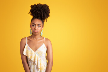 Wall Mural - Sad upset offended pretty millennial black woman in dress looking at camera