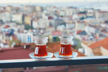 Wall Mural - Two Turkish glasses filled with tea with view to the roofs of Uskudar district on Asian side of Istanbul, Turkey