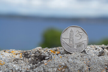 Wall Mural - Cuban escudo coin on a rustic wall with seascape in a background