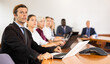 © JackF - Man in suit sitting at table with his colleagues, attending meeting and using laptop.