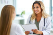 © MVProductions - Female doctor with clipboard talking to smiling woman patient at hospital