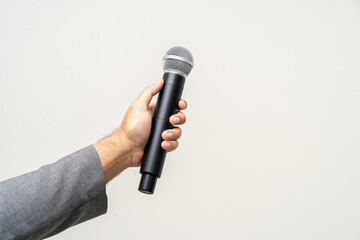 Canvas Print - Close up businessman speaker hand holding High quality dynamic microphone and singing song or speaking talking with people on isolated white background. Male testing microphone voice for interview